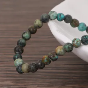 Afrikanisches Türkis-Perlenarmband mit natürlichen erdig-blauen Steinen auf Holzgrund