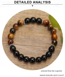 Dettaglio delle perle in occhio di tigre e onice nero su sfondo di legno naturale.