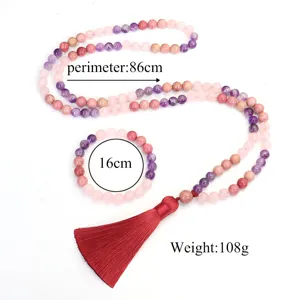 Primo piano di collana e bracciale yoga con 108 perle di cristallo rosa e viola e nappa rossa