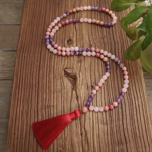 Dettaglio della collana yoga con 108 perle di quarzo rosa e ametista e nappa di seta rossa