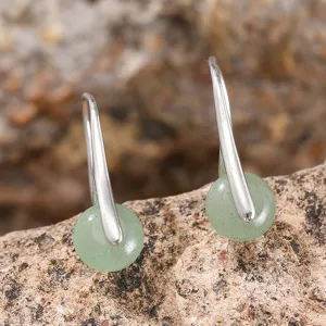 Elegante Ohrhänger mit grünem Rundstein und Silberhaken auf natürlichem Felsgrund