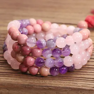 Dettaglio ravvicinato di 108 perle di quarzo rosa e ametista su sfondo in legno