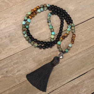 Primo piano di una collana mala da 108 grani con pietre occhio di tigre e nappa nera lunga
