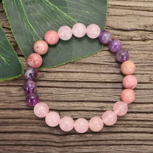 Primer plano de pulsera de yoga con cuentas de cuarzo rosa y amatista en una hoja.