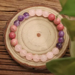 Dettaglio macro di un braccialetto yoga in quarzo rosa e ametista su legno vero