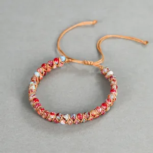 Dettaglio ravvicinato di perle di diaspro da 4mm con cordino marrone intrecciato a mano