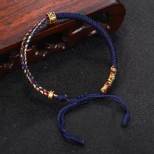 Dettaglio macro di braccialetto tibetano intrecciato a mano con perla mantra in rame