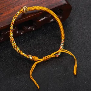 Dettaglio macro di un braccialetto tibetano intrecciato a mano con nodo Vajra dorato