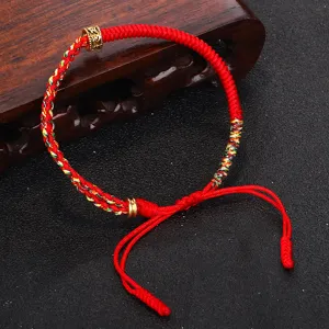 Dettaglio del braccialetto tibetano fatto a mano con corda rossa e perla mantra oro.