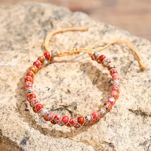 Vista macro dettagliata del bracciale yoga in diaspro imperiale da 4 mm intrecciato su roccia