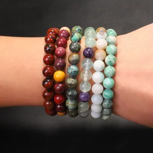 Nahaufnahme von mehreren Naturstein-Armbändern, die am Handgelenk gestapelt sind.