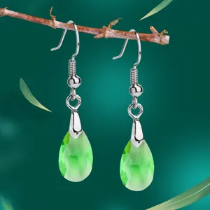 Elegante grüne Kristallohrringe in Tropfenform mit silbernen Haken an einem Zweig.