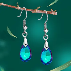 Elegante Tropfen-Kristallohrringe mit schillerndem Teal-Finish auf Deko-Zweig