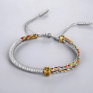 Bracciale tibetano intrecciato a mano con nodi colorati e una perla mantra dorata.