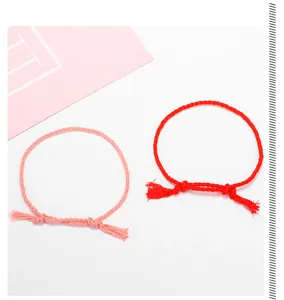 Detailaufnahme von handgeflochtenen Baumwollarmbändern in Rot und Rosa mit Quasten