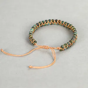 Close-up view of a hand-woven 4mm African turquoise bead bracelet with adjustable cord