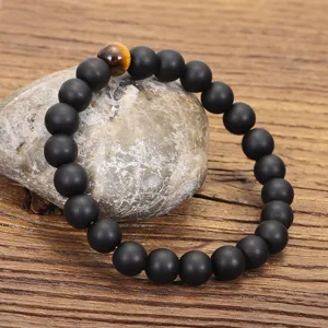 Primer plano detallado de una pulsera de cuentas negras mates con piedra ojo de tigre
