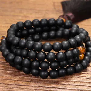 Primer plano detallado de un collar mala de 108 cuentas negras mate y ojo de tigre.