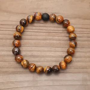 Vista dettagliata di un bracciale di perle di occhio di tigre naturale su uno sfondo di legno testurizzato.