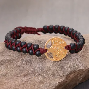 Close-up of handmade braided bracelet with matte beads and gold Tree of Life charm.