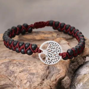 Detailed view of matte black bead bracelet with a silver Tree of Life metal charm