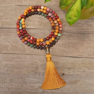 Detailed view of a 108-bead mala necklace with natural stones and yellow tassel on wood