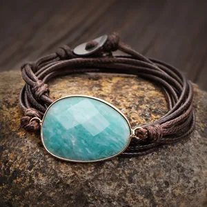 Dettaglio di pietra amazonite sfaccettata con bordo dorato su bracciale in cordino cerato