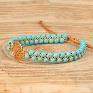Detail van een handgemaakte turquoise kralenarmband met gouden levensboom-hanger