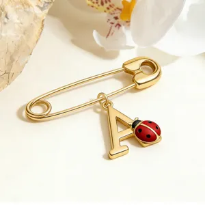 Exquisite detail of a gold-plated ladybug and letter A charm safety pin brooch.