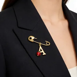 Detail of gold-plated silver safety pin brooch with ladybug and letter A charms