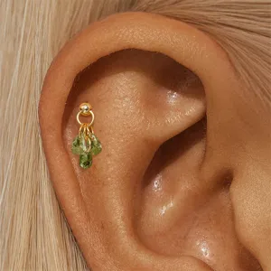 Gros plan d'une boucle d'oreille en argent 925 avec grappe de zircons verts sur l'oreille