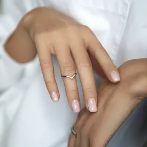 Primo piano di un anello minimalista in argento 925 a forma di V su un dito.