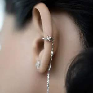 Close-up detail of a 925 sterling silver star ear cuff with zircon and tassel chain