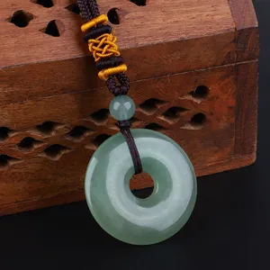 Nahaufnahme einer grünen Steindonut-Halskette mit geflochtener Kordel auf Holzbox.