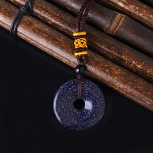 Nahaufnahme des blau funkelnden Goldfluss Ping'an Kou Anhängers mit Kordelband