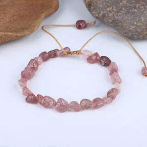Primo piano di un bracciale fatto a mano con frammenti di quarzo fragola rosa irregolari.