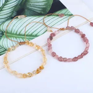 Dettaglio di bracciali intrecciati a mano con cristalli naturali gialli e rosa irregolari.