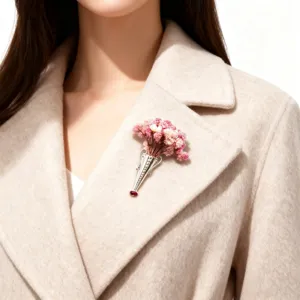 Detailed view of an elegant S925 silver vase brooch with pink flowers on a beige coat