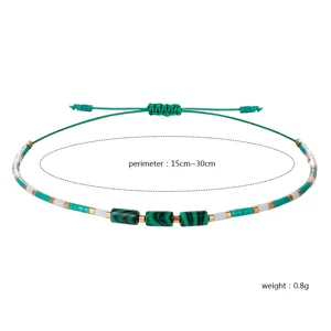 Detailansicht eines handgefertigten 2mm Perlenarmbands mit zylindrischen grünen Steinen