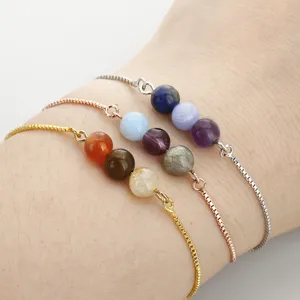 Nahaufnahme von drei zierlichen Perlenarmbändern mit Gold-, Roségold- und Silberketten am Handgelenk