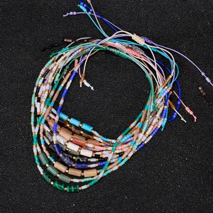 Nahaufnahme bunter handgefertigter Armbänder mit 2mm Perlen und kleinen Steinzylindern