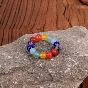 Nahaufnahme von 4mm bunten Natursteinperlen auf einem elastischen Yoga-Ring auf einem Stein