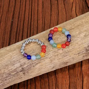 Makroaufnahme von 4 mm bunten Edelstein-Elastikringen für Yoga auf Naturholz-Hintergrund.