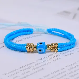 Detalle del brazalete de cuentas azules con detalles dorados y dije de ojo turco de la suerte.