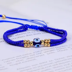 Primer plano de una pulsera de cuentas azules con ojo turco y cordón ajustable oro.