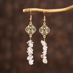 Détail de boucles d'oreilles dorées avec éclats de cristal clair et motifs de géométrie
