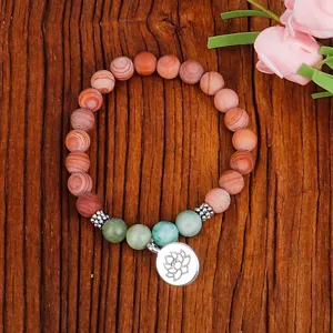Détail d'un bracelet en perles de bois avec pierres vertes et breloque lotus