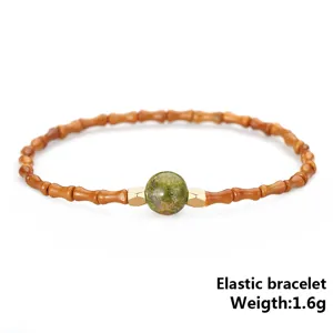 Macro view of olive core bamboo joint elastic bracelet with green stone bead, 1.6g