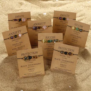 Detail of handmade stone bracelets with symbolic cards on a sandy beach setting