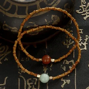 Macro detail of two bamboo-joint beaded bracelets with strawberry crystal and jade beads